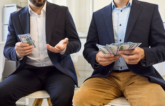 Employees workers men show salary wages inequality disparity. Two colleagues in suits compare cash during payroll as unfairness in comparison leaves one holding less. Symbol of workplace pay gap.