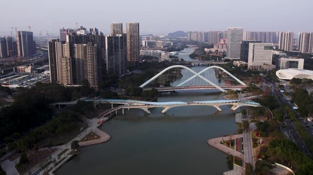 Aerial view of modern urban area with multiple bridges spanning a river, surrounded by high-rise buildings and green spaces.