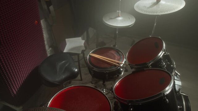 Drum kit standing in empty music recording studio under spotlight with smoke. Footage for music school advertisements, musical instrument retail promos or band concert trailers