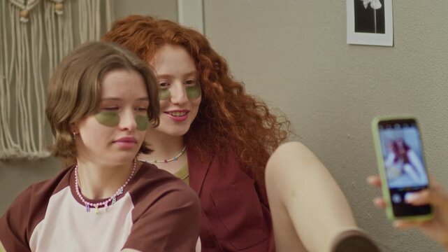 African American girl taking photo of her Caucasian friends wearing eye patches and posing. Ideal for skincare brands, youth lifestyle apps, and social media marketing campaigns