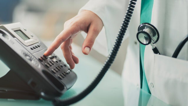 Doctor answering office phone at medical desk