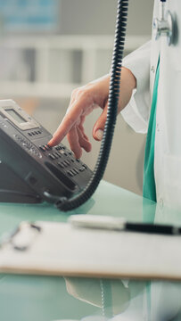 Doctor answering office phone at medical desk