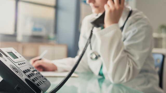 Doctor answering office phone at medical desk
