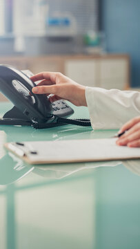 Doctor answering office phone at medical desk