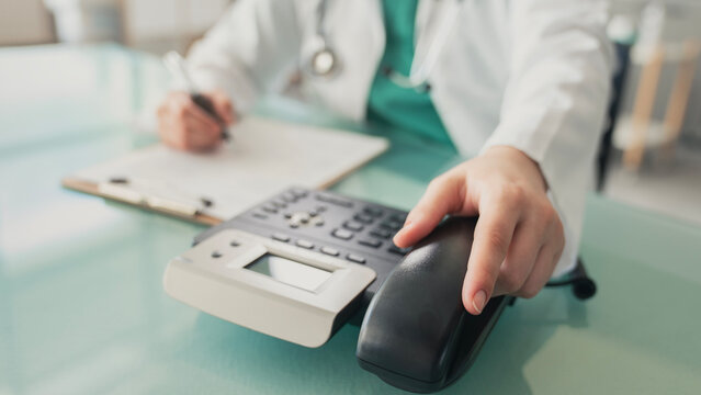 Doctor answering office phone at medical desk