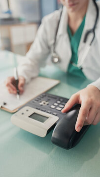 Doctor answering office phone at medical desk