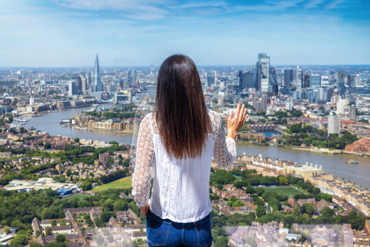 Rear view of a tourist woman looking at the panoramic view of the skyline of London, England, during a sunny summer day