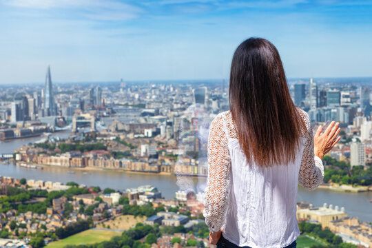 A woman looks at the elevated view of the cityscape of London, England, on a sunny summer day