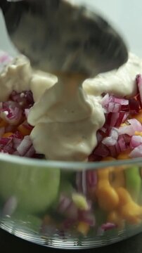Adding Creamy Dressing to Fresh Cucumber, Corn, and Red Onion Salad