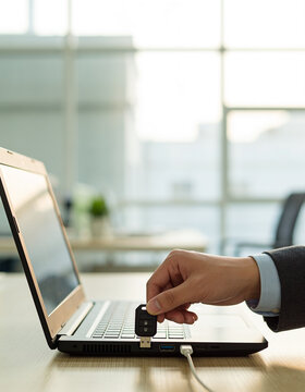 Hand inserting card into laptop security reader in office