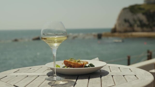 Seaside restaurant table with white wine and fish dish