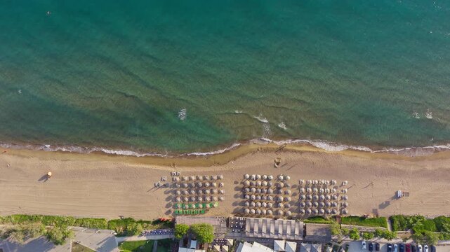 Overhead aerial view of Kourouta beach bars, sunbeds and natural straw umbrellas in the shallow waters of Ionian Sea, Ilia