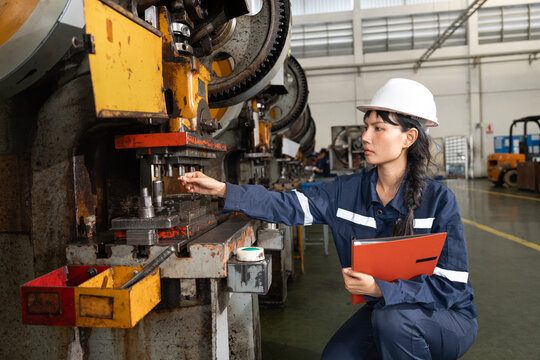 Female factory worker inspecting machinery in industrial plant