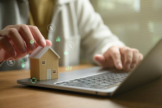 Digital mortgage and home loan concept featuring a wooden house model on a laptop with financial icons, online banking, property investment, real estate financing, smart financial planning.