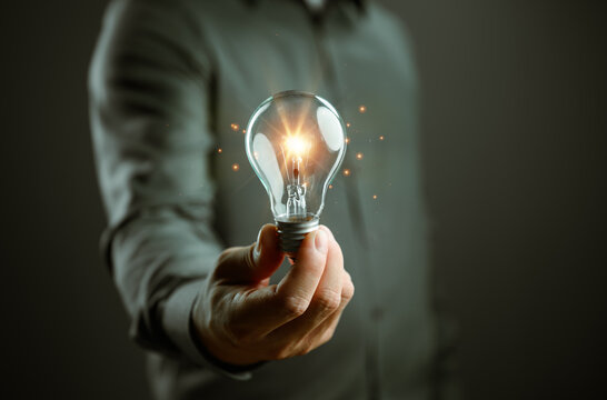 Innovation concept featuring a glowing light bulb held in a hand, symbolizing creative ideas, business strategy, problem solving, entrepreneurship, leadership, inspiration, and future success.