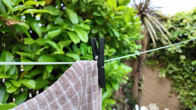 Clothes Pegs On Washing Line With Towel Drying In Green Back Garden