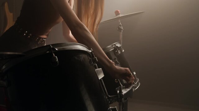 Woman adjusting drum kit and playing drums with drumsticks in music studio. Clip for music school ads, instrument retail promos, or band marketing campaigns