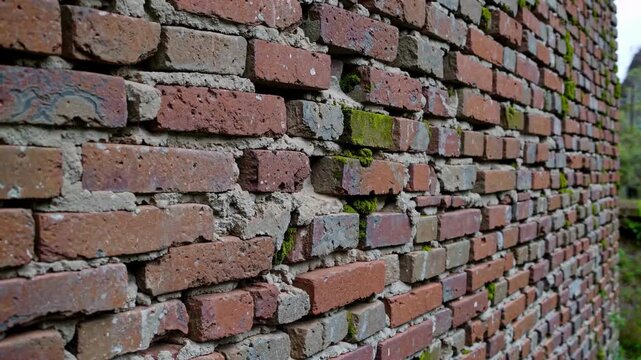 Closeup Weathered Brick Wall With Moss Showing Cracked Mortar, Crumbling Bricks, Gritty Surface And Subtle Outdoor Light Ideal For Background, Architecture Study, Restoration Reference, Or Urban