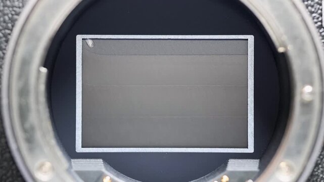 Extreme close-up of a mirrorless camera sensor with the mechanical shutter curtain triggering as it rapidly moves up and down, revealing the precision and speed of modern camera technology.
