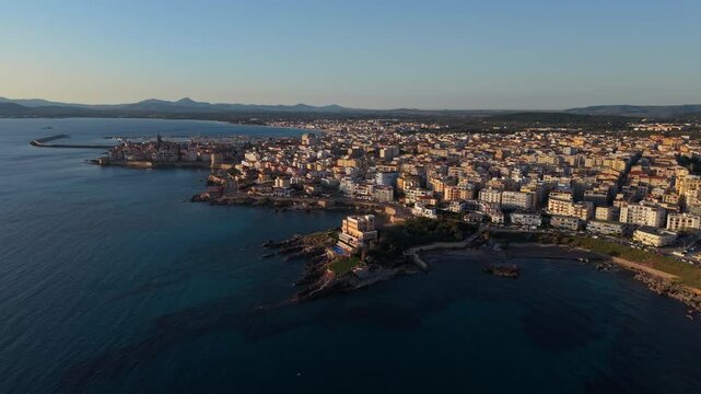 Historic Coastal Town Of Alghero By Turquoise Sea At Sunrise In Sardinia. - aerial shot