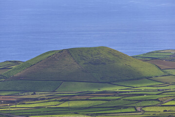 Volcanic landscape featuring green fields, stone walls, and the atlantic ocean © ANTONIO COSTA