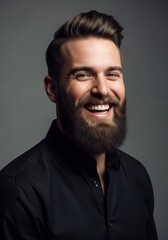Obraz premium Portrait of a Handsome Smiling Man with a Well-Groomed Beard and Stylish Haircut Wearing a Black Shirt on a Grey Background