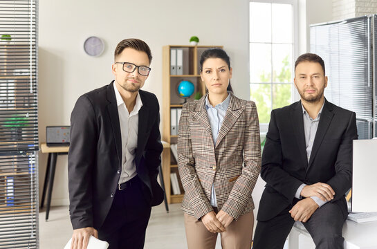Team business people portrait in modern office. Three coworkers in professional attire look at camera. Ideal for leadership uses manager and executive. Clear teamwork and leadership concept.