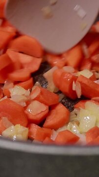 Diced Onions and Carrots Saut&eacute;ing in Hot Oil in Pot Close Up