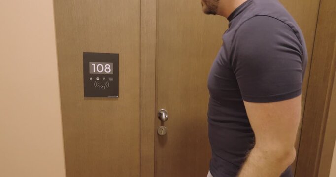 Man searching for his missing hotel key card outside his hotel room and unable to enter. Travel concept of lost room key, hotel access problems, and accommodation inconvenience.