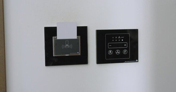 Close-up of a person inserting a hotel key card into the room power slot to activate electricity. Travel concept of hotel access, energy saving, and accommodation convenience.