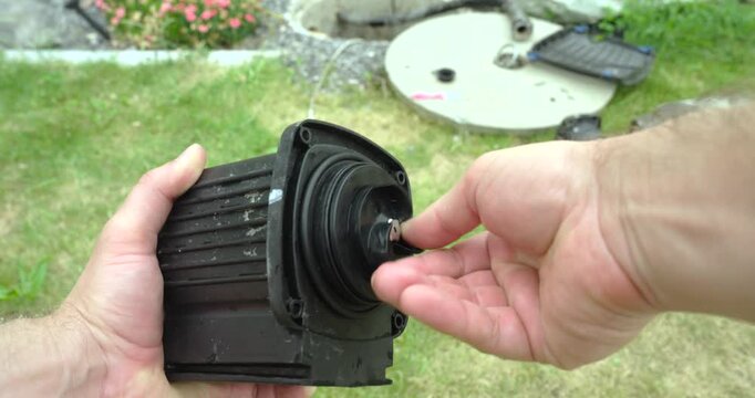 Close-up of a person inserting and rotating the pump rotor into the stator during reassembly after descaling. Maintenance concept of pump repair, servicing, and mechanical assembly.