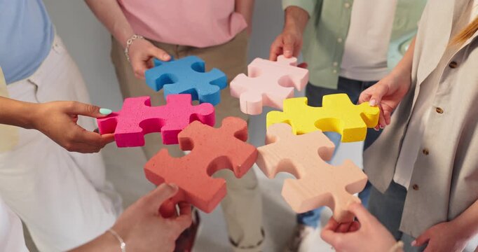 People hands hold puzzle pieces for teamwork. Group collaboration and cooperation show a team uniting, with bright pieces symbolizing problem solving. Clear concept of unity and teamwork.