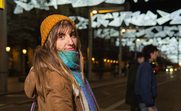 Woman enjoying festive city street illuminated at night