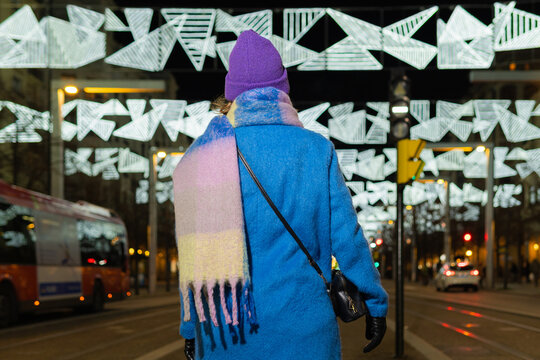 Woman walking city street during winter festive night