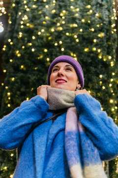 Woman enjoying festive christmas lights feeling cozy outdoors