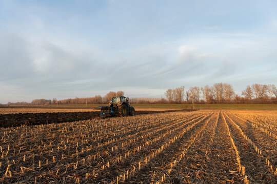 Red tractor plowing agricultural field after harvest, soil cultivation and farm work