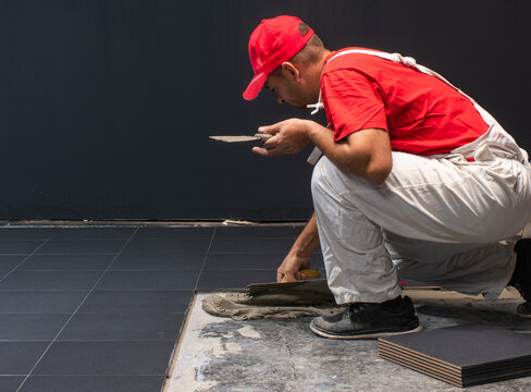 Professional Tiler Installing Large Dark Ceramic Floor Tiles