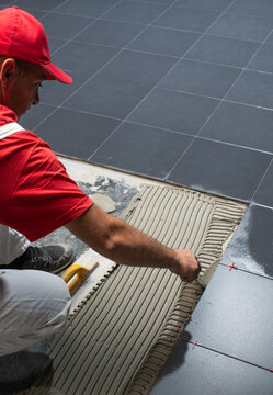 Professional Tiler Installing Large Dark Ceramic Floor Tiles