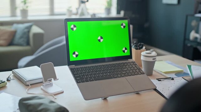 No people shot of laptop computer with green screen and tracking markers on office desk. Perfect for showcasing software, website design, or digital product mockups in corporate marketing videos