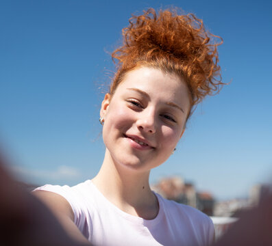 Point of view of a young redhead woman smiling and taking a selfie, first-person view