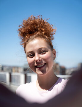 Point of view of a young redhead woman smiling and taking a selfie, first-person view