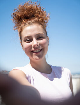 Point of view of a young redhead woman smiling and taking a selfie, first-person view
