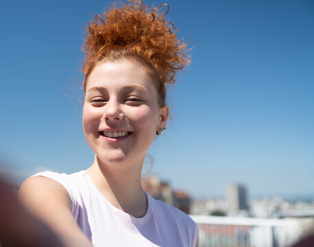 Point of view of a young redhead woman smiling and taking a selfie, first-person view