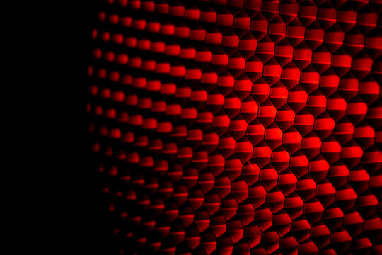 Closeup honeycomb grid texture with red light. Red and dark metal hexagon shaped pattern abstract background. Light modifier equipment. Metal honeycomb. Futuristic pattern. Honey grid cells network.