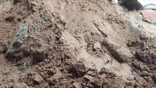 Worker digging sand and soil with a hoe tool at a construction site