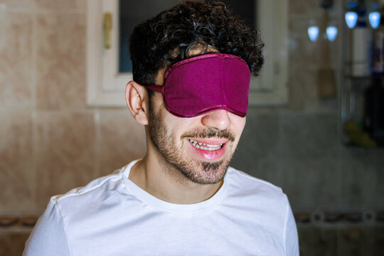 Smiling man wearing sleep mask practicing self-care and morning wellness routine