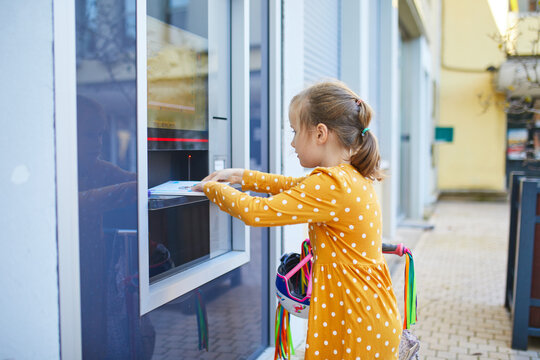 Young girl returning books through an outdoor library self-service machine