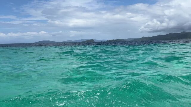 Point of view shot of Sailing in Raja Ampat sea, Indonesia, showing the color contrast between the different sea depth.  Showing friwen island and yanbesir area in the background