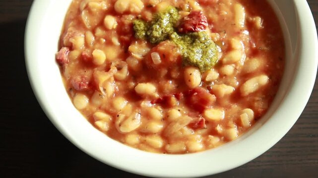 Serving Delicious Bean Stew with Sun Dried Tomatoes in Bowl Close Up
