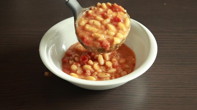 Serving Delicious Bean Stew with Sun Dried Tomatoes in Bowl Close Up